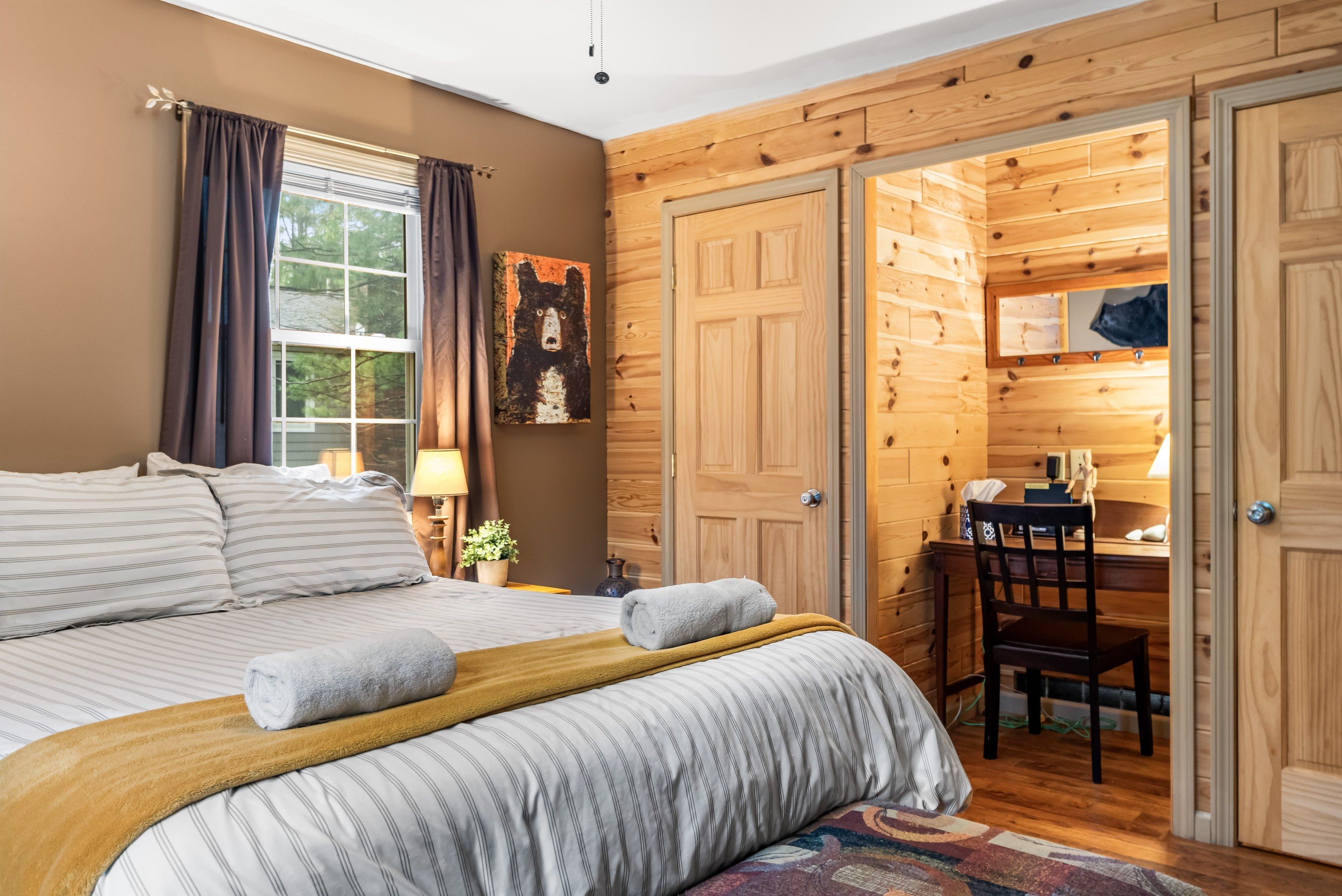 A bedroom with a bed, a desk, and a chair.