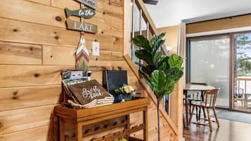 A wooden wall with a welcome sign, a guest book, and a small table with a plant and a bottle.