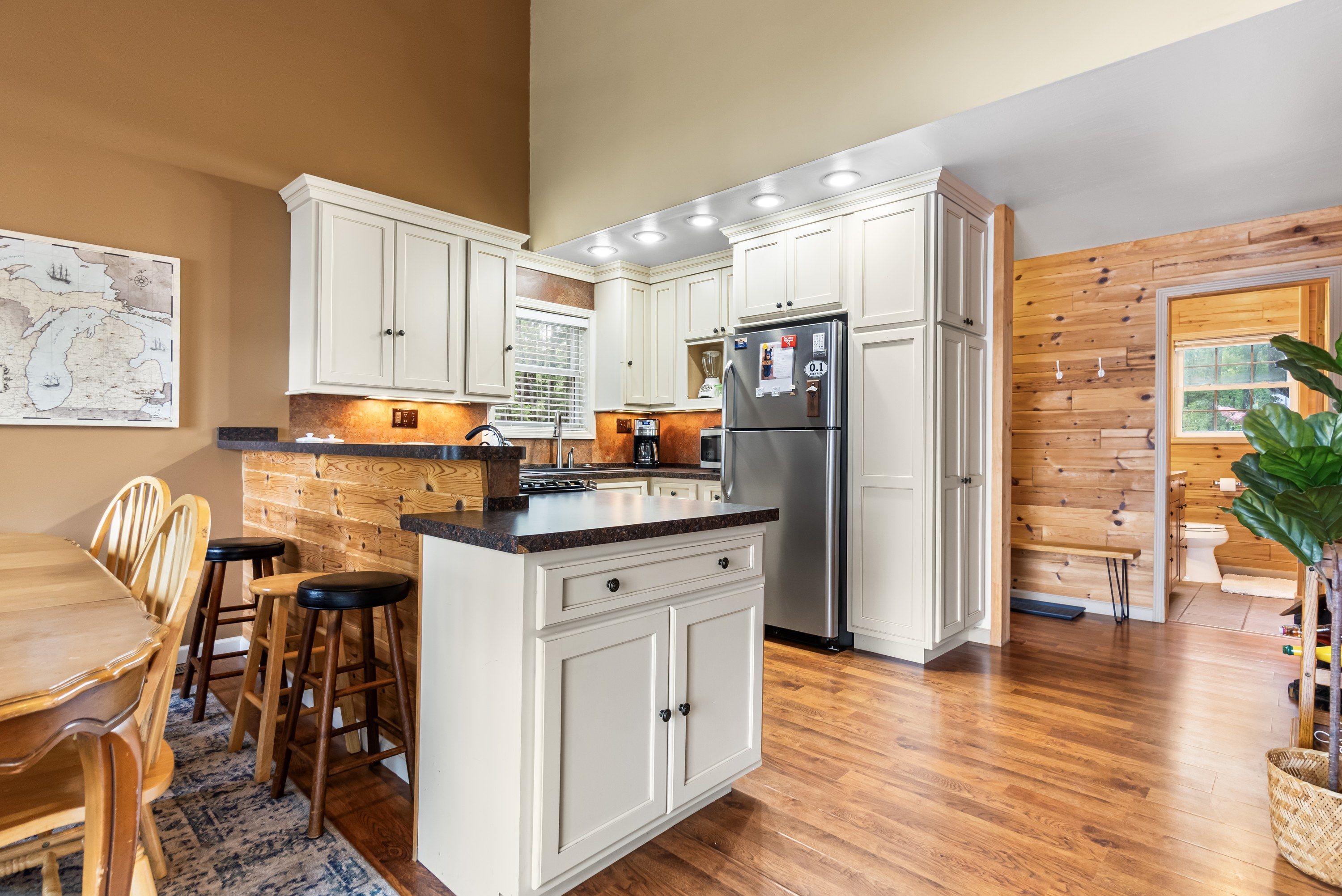 A modern kitchen with white cabinetry, a central island, and a stainless steel refrigerator.