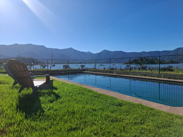 A pool with a view of mountains, a chair, and a fence.