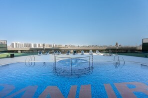 A rooftop swimming pool with a cityscape view, lounge chairs, and a clear sky. - Stayshort - Peaceful 2-bedroom in Al Furjan That Sleeps 6 (Dubai)