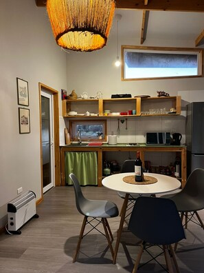 Cocina compacta con comedor, que incluye una mesa redonda, sillas, una lámpara colgante y vistas al exterior.