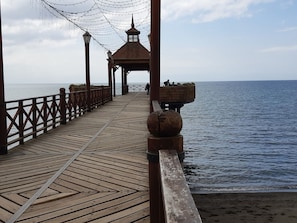 Un muelle de madera que lleva a un quiosco con vista al mar.