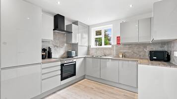 A modern kitchen with white cabinetry, a built-in oven, a microwave, and a window providing natural light.
