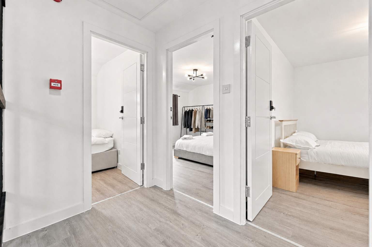A modern hotel room with a bed, bedside table, and a wardrobe.