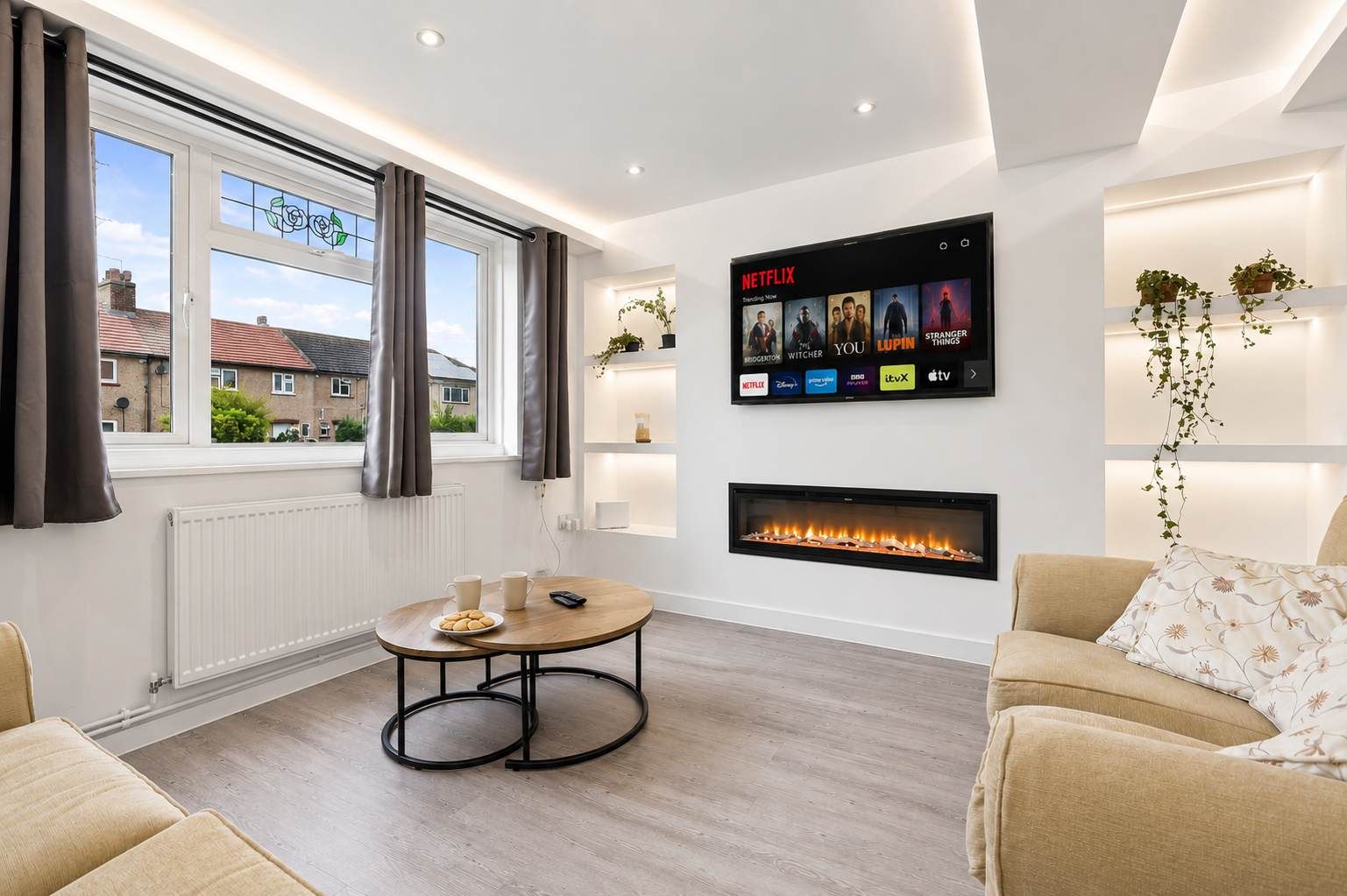 A modern living room with a fireplace, a mounted TV displaying Netflix, and a view of the outside.