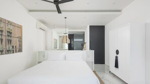 A modern bedroom with a large bed, a ceiling fan, a mirror, and a door leading to a bathroom. - 5 Star Golden Lotus Villas – Hilltop Luxury (Chang Wat Surat Thani)