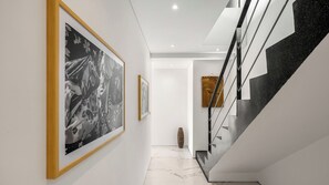 A hallway with a staircase, framed artwork on the walls, and a vase on the floor. - 5 Star Golden Lotus Villas – Hilltop Luxury (Chang Wat Surat Thani)