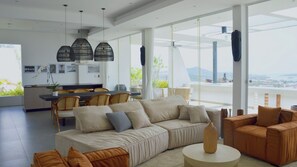 A modern living room with a sofa, chairs, a dining area, and large windows offering a view of the outdoors. - Idyllic 4-Bed Villa in Amphoe Ko Samui, Sleeps 8, 1019 (Chang Wat Surat Thani)