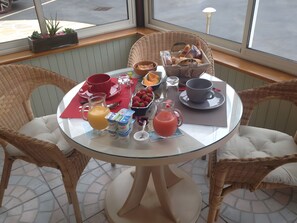 A breakfast table with wicker chairs, a glass table, and a view of the street outside. - Guest Room “L’hermine Blanche” with Wi-Fi (Calorguen)
