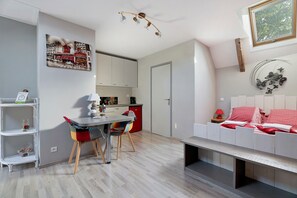A modern interior with a dining area, kitchen, and a bedroom with a bed and decorative wall art.