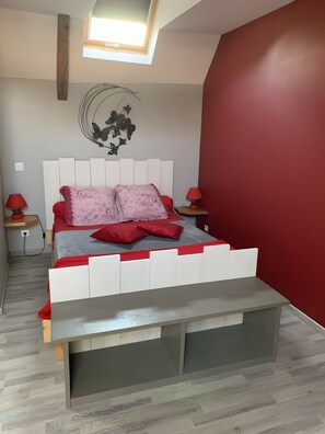 A bedroom with a bed, a red wall, a skylight, and a nightstand with a lamp. - Guest Room “L’hermine Blanche” with Wi-Fi (Calorguen)