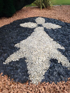 Un mosaico de piedritas con la figura de un ser humano en un jardín.