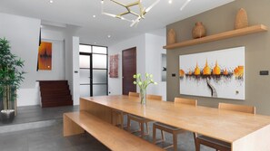 A modern dining area with a long wooden table, benches, and a vase with flowers. - Tranquil Escape in Koh Samui, Koh Samui Villa 1021 (Koh Samui)