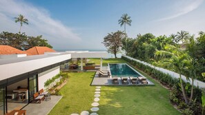 Una casa moderna con piscina, mobiliario exterior y vistas al océano.
