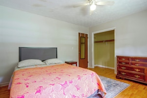 Un dormitorio con cama, cómoda, ventilador de techo y una puerta que da a un armario.