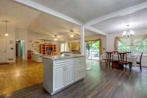 Cozinha ampla com ilha central, piso de madeira e área de jantar com mesa e cadeiras.