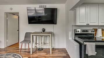 A modern kitchen with white cabinets, a built-in oven, and a flat-screen TV mounted on the wall.