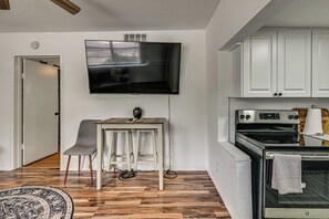 A modern kitchen with white cabinets, a built-in oven, and a flat-screen TV mounted on the wall. - South Tampa Apt Near Macdill & Bayshore (Tampa)