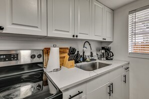 A kitchen with white cabinets, a stainless steel stove, a sink, and a window with blinds. - South Tampa Apt Near Macdill & Bayshore (Tampa)