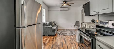 Cocina compacta con refrigerador, estufa y ventilador de techo.
