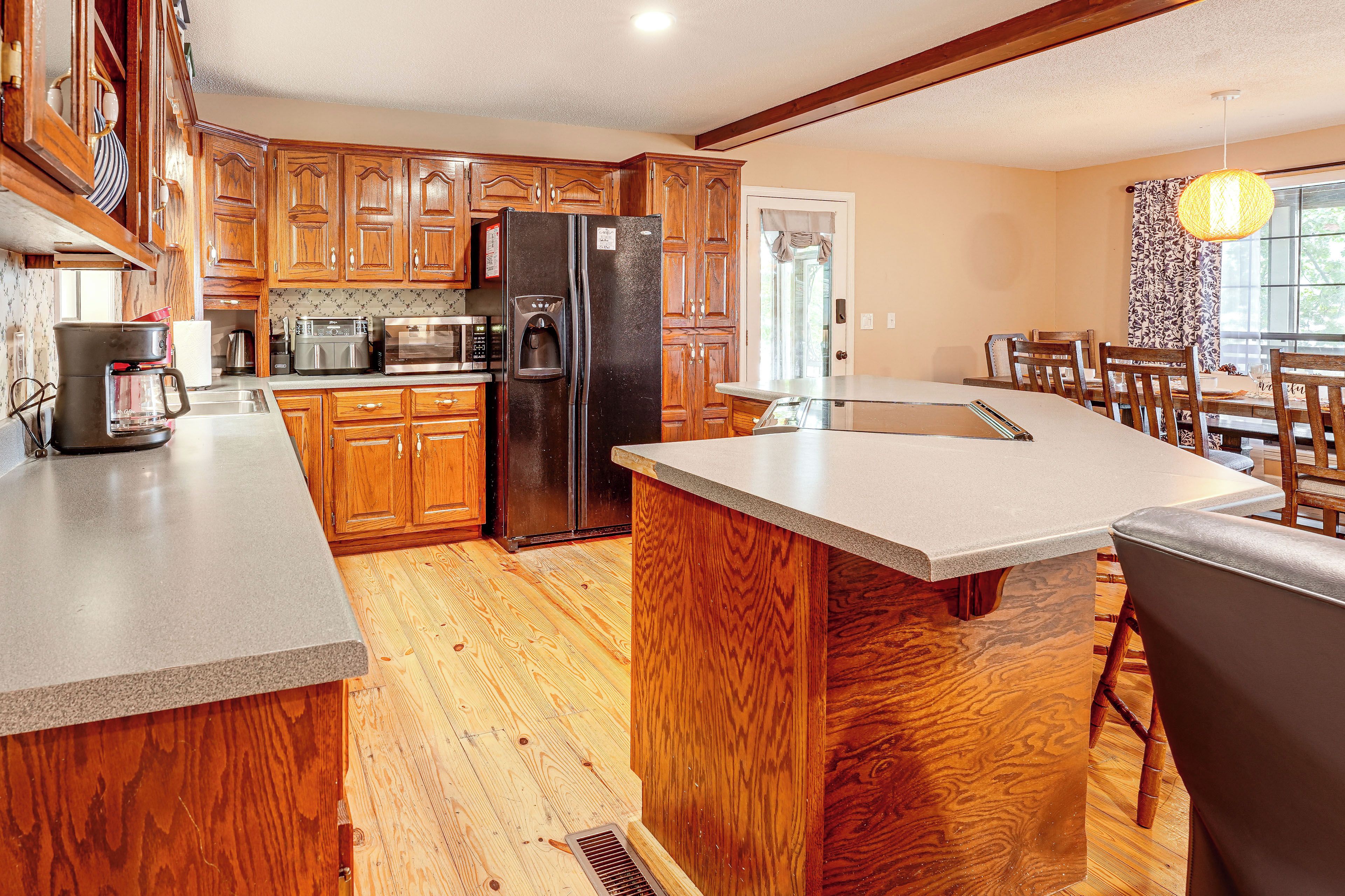 A kitchen with wooden cabinets, a refrigerator, a coffee maker, and a dining area with a table and chairs.
