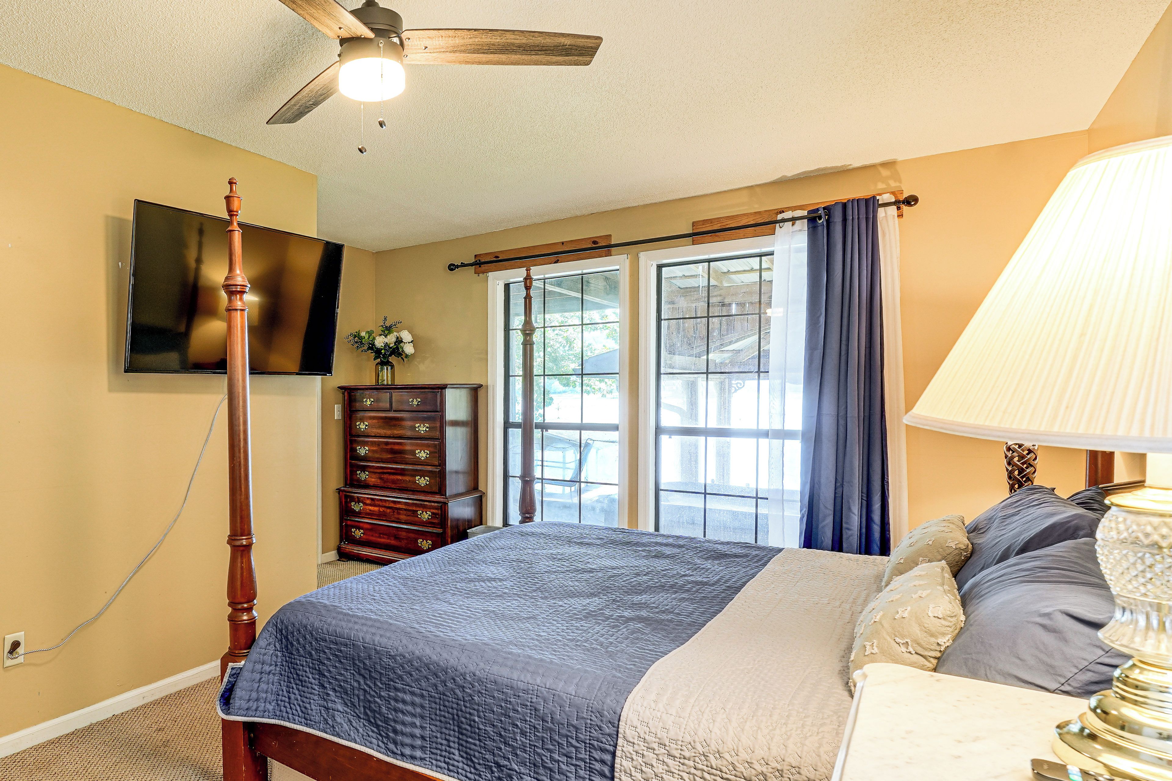 A bedroom with a bed, a dresser, a television, and a ceiling fan.