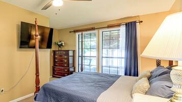 A bedroom with a bed, a dresser, a television, and a ceiling fan.