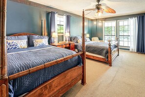 A four-poster bed with a wooden frame and a dark blue quilt.