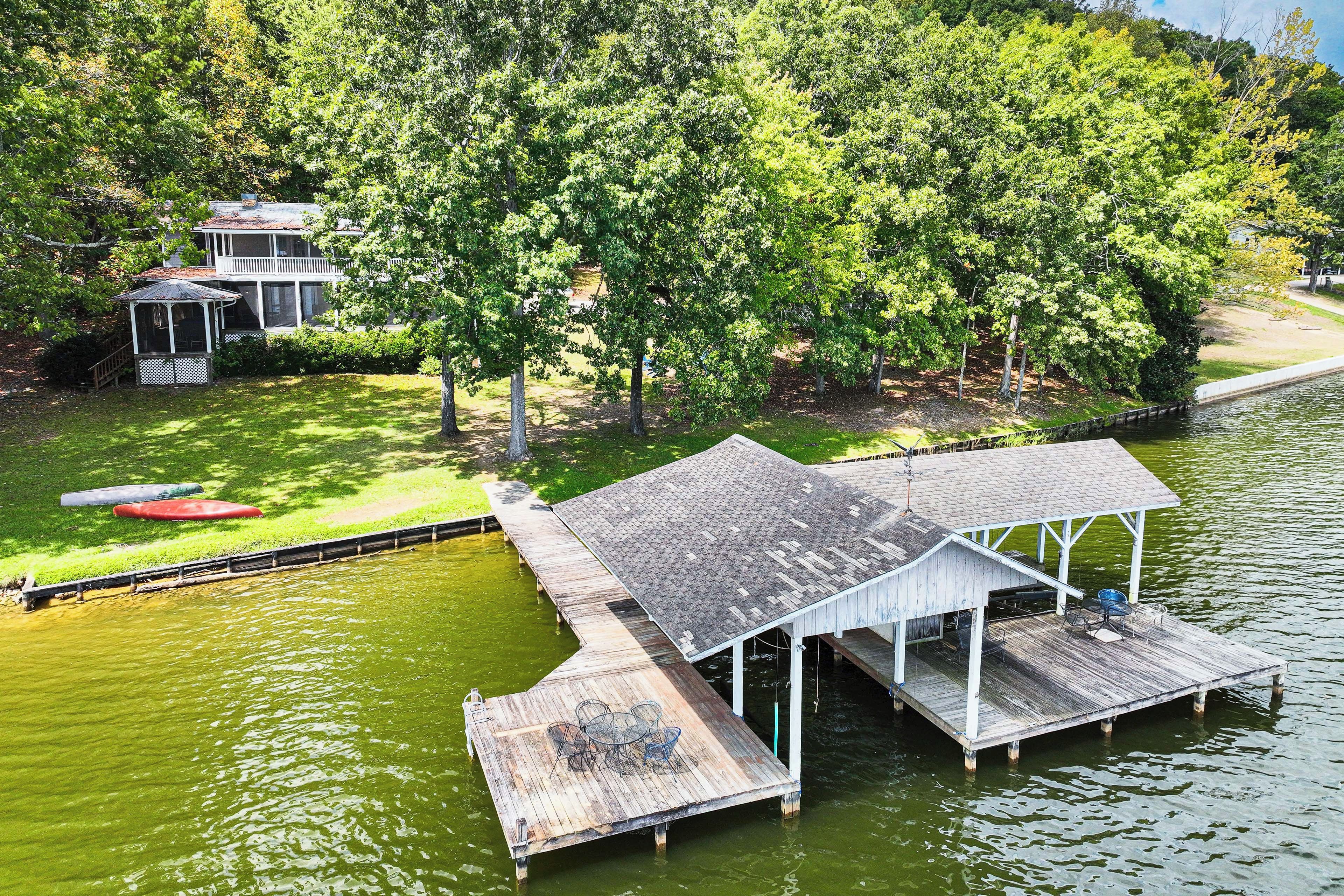 A dock extending into a body of water with a covered seating area and a small pavilion.