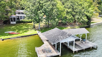 A dock extending into a body of water with a covered seating area and a small pavilion.