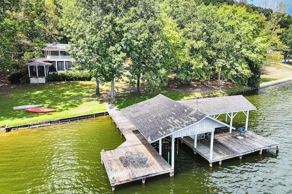 A dock extending into a body of water with a covered seating area and a small pavilion.