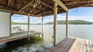 A wooden dock extending into a calm lake with a clear sky and distant hills.