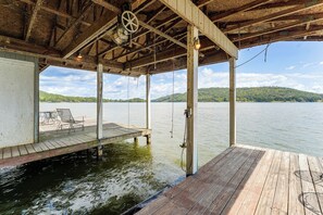 A wooden dock extending into a calm lake with a clear sky and distant hills.