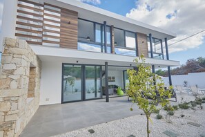 Ein modernes, zweistöckiges Haus mit Natursteinfassade, großen Glasfenstern und einem Flachdach.