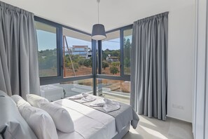 Een moderne slaapkamer met een groot bed, een nachtkastje en uitzicht op de omgeving.