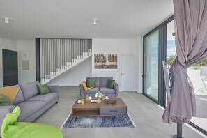 Ein modernes Wohnzimmer mit einem grauen Sofa, einem Holztisch und einer Treppe.
