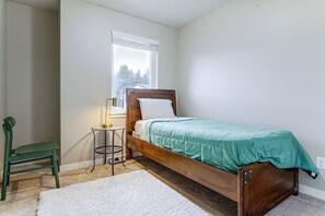 A bedroom with a wooden bed, a green chair, a small round table, and a window with blinds. - All-seasons Everett Escape w/ Private Balcony! (Everett)
