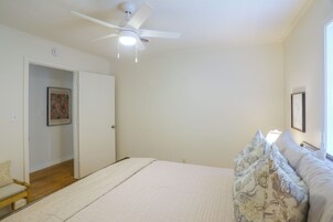 Un dormitorio con cama, ventilador de techo, puerta y ventana.