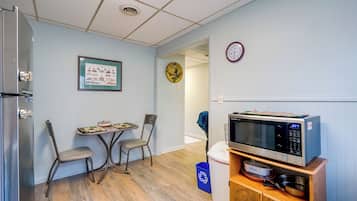 A compact kitchen with a microwave, a small dining table, two chairs, and a refrigerator.