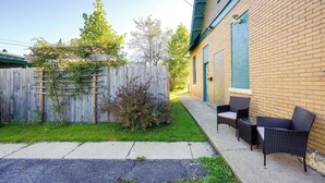 A patio area with outdoor furniture, a wooden fence, and a brick building.