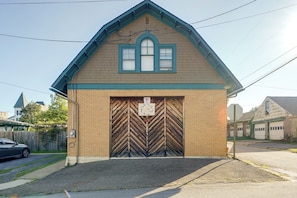 A small building with a pitched roof, a wooden door with a sign, and a brick facade.