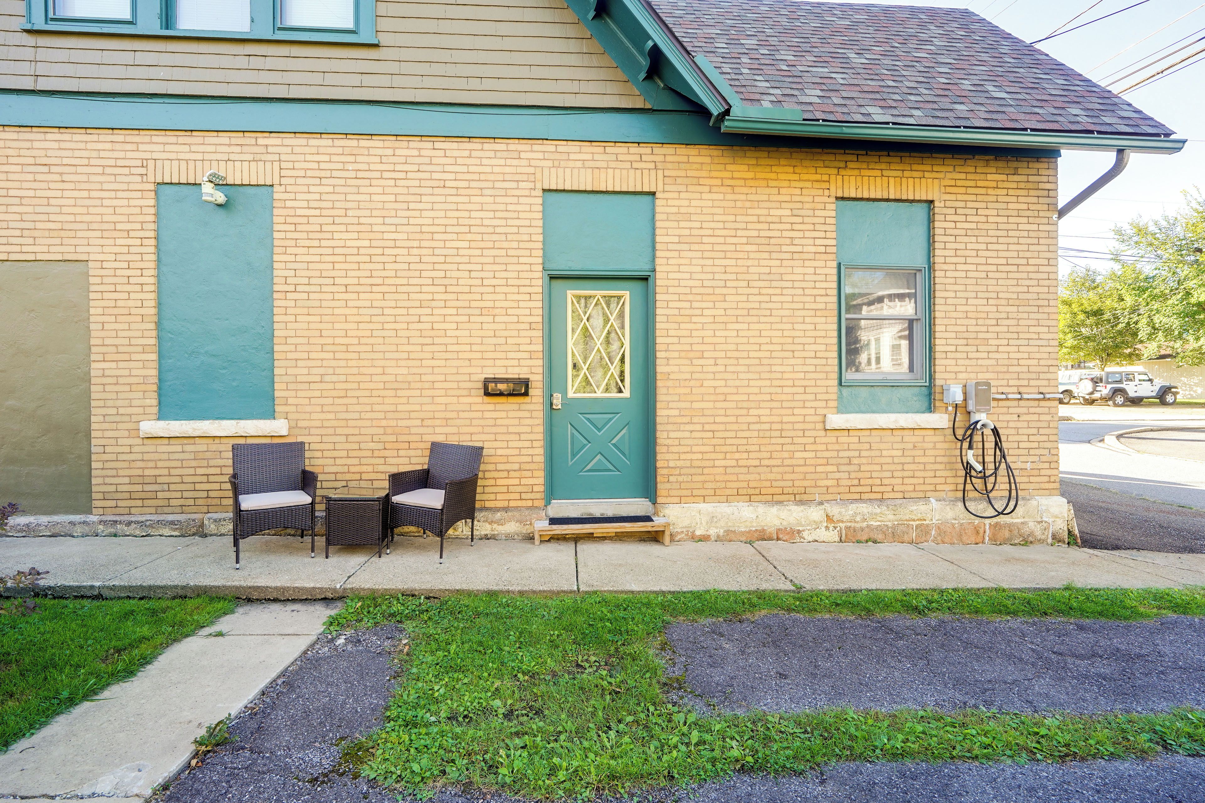 A building with a brick facade, a green door, and two wicker chairs outside.