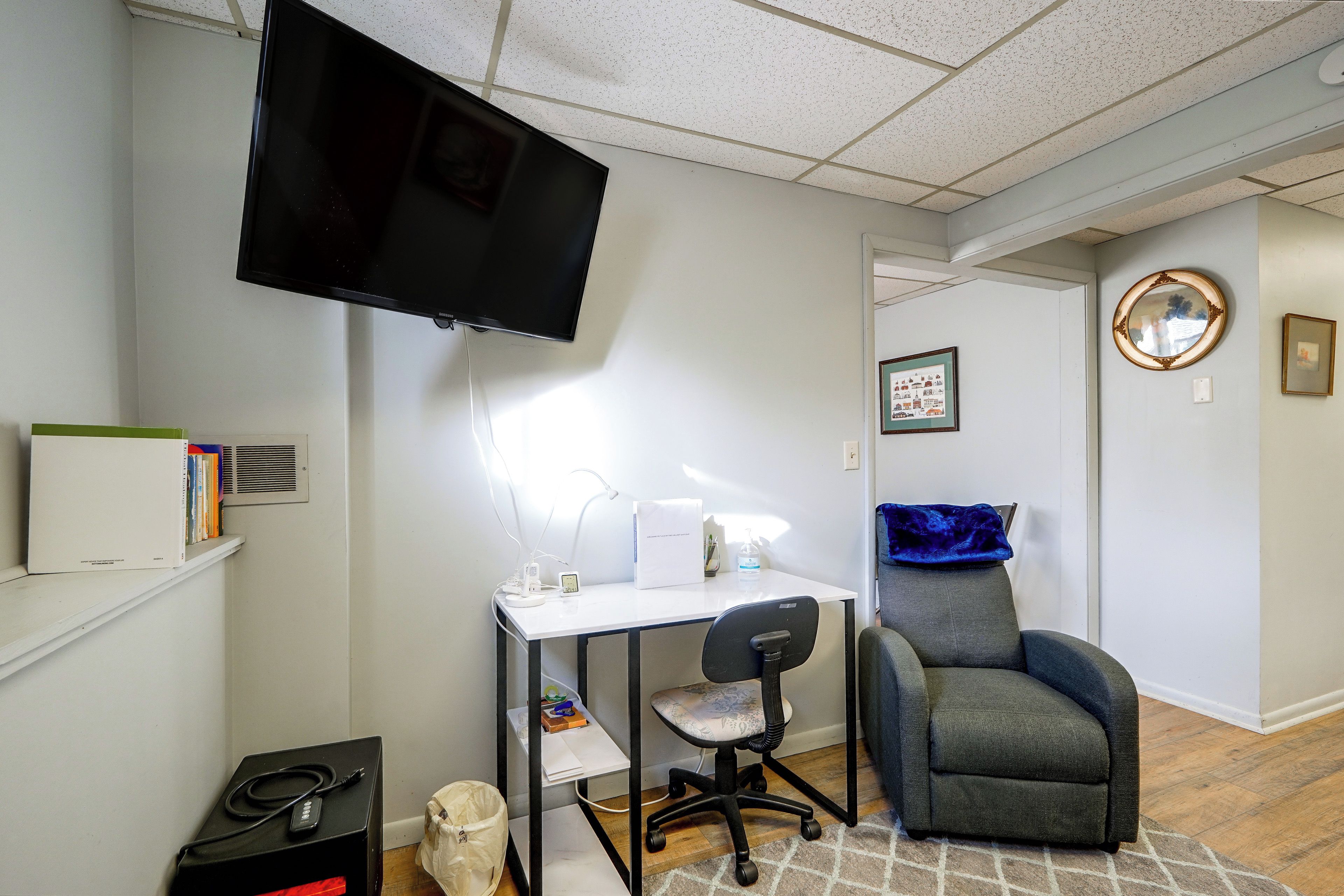 Una habitación con escritorio, silla, televisor y estantería.