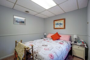 Un dormitorio con cama, mesita de noche, lámpara y un cuadro en la pared.