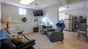 A compact living space with a sofa, a small table, a TV, and a kitchenette area.