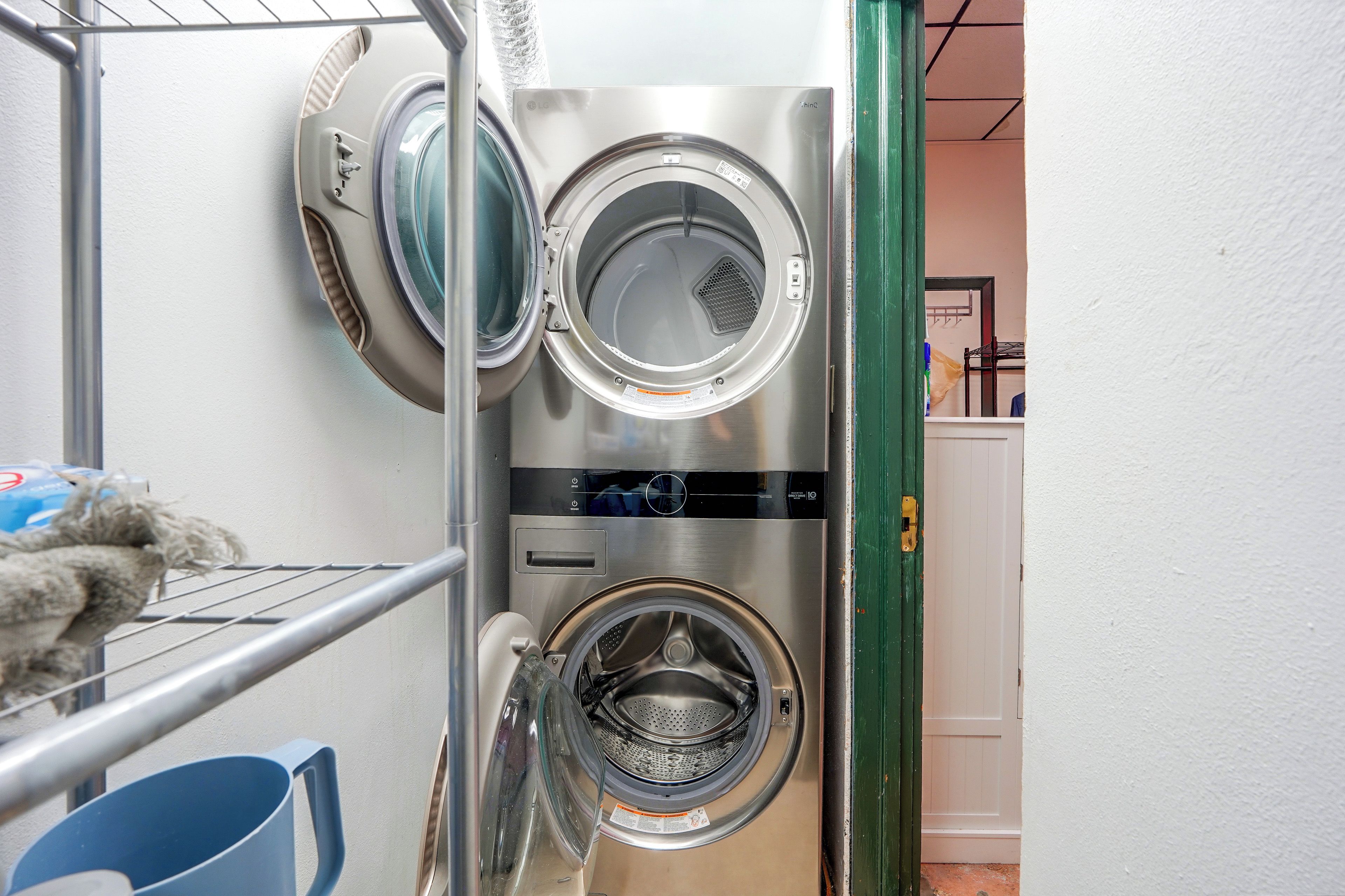A laundry area with two stacked washing machines and a drying rack.