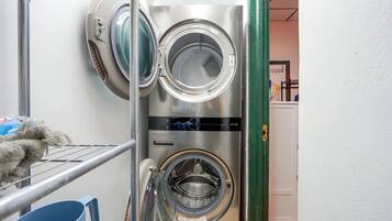 A laundry area with two stacked washing machines and a drying rack.