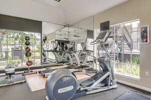 Un gimnasio con equipo de ejercicio, un espejo grande y vistas al exterior.