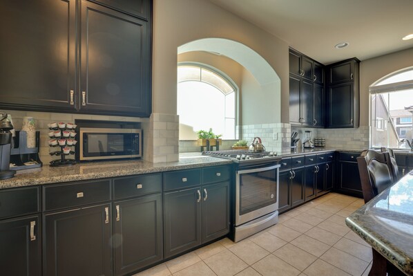 A modern kitchen with dark cabinetry, a built-in microwave, and a stainless steel range.